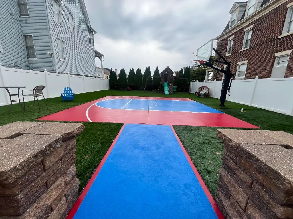 After backyard sport court repaint from entry view with blue walkway and red court